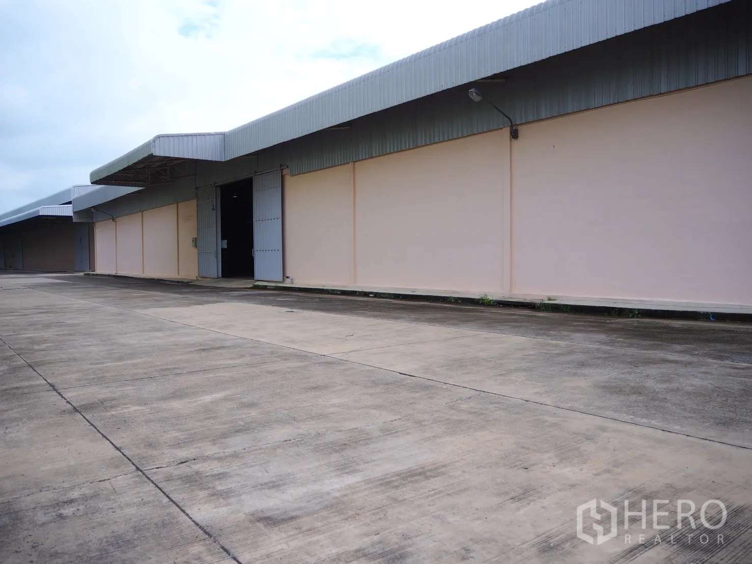 Factory for rent in Uthai, Phra Nakhon Si Ayutthaya - Factory exterior with metal awnings, large steel doors, and a wide concrete driveway for trucks.