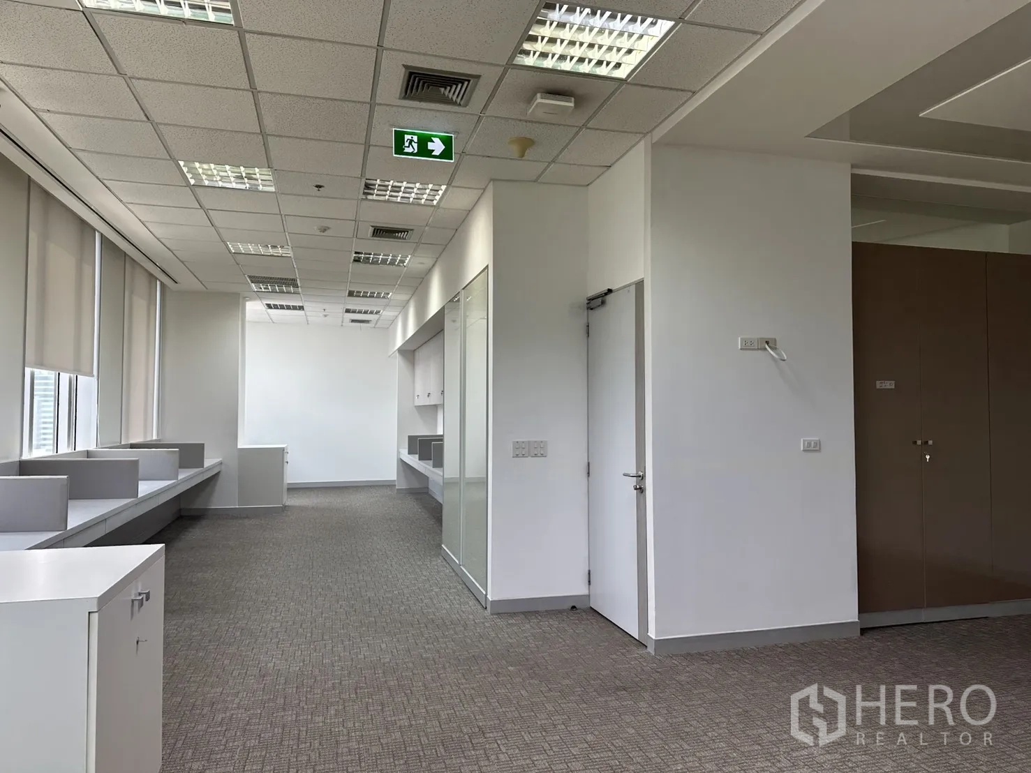 Office Space for rent in Khlong Toei, Bangkok - Long office zone with T-bar ceiling lights, exit sign, and multiple desks.