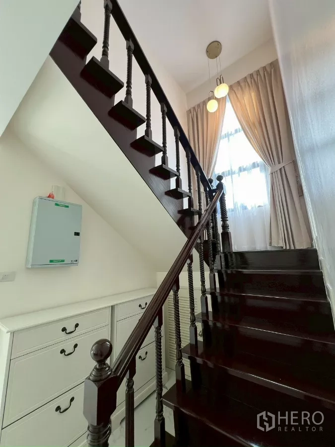 Detached House for rent in Suan Luang, Bangkok - Polished dark-wood staircase with classic balusters and a tall window.
