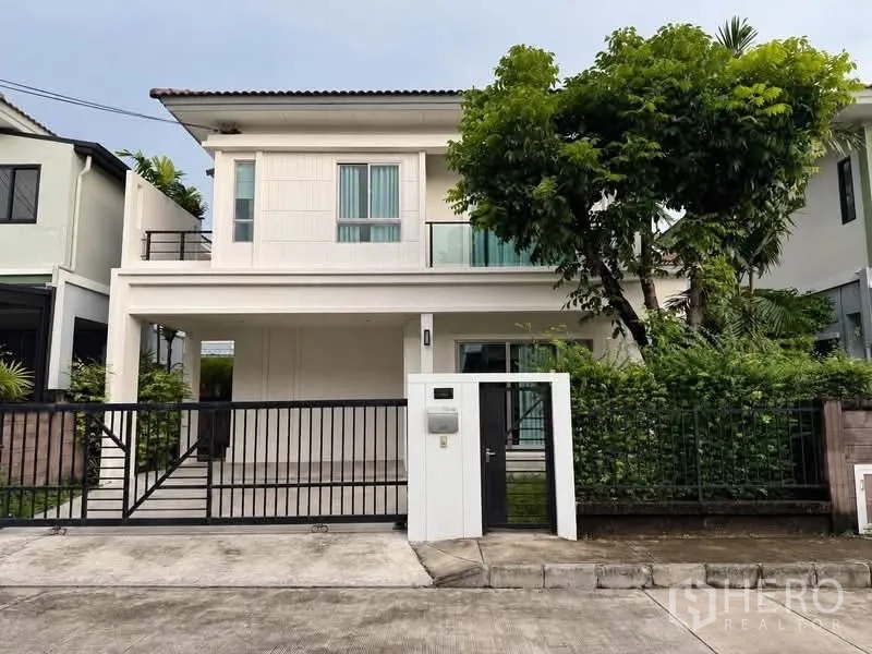 Semi-detached House for rent or sale in Suan Luang, Bangkok - Modern two-storey semi-detached house exterior with covered carport, balcony, and front gate.