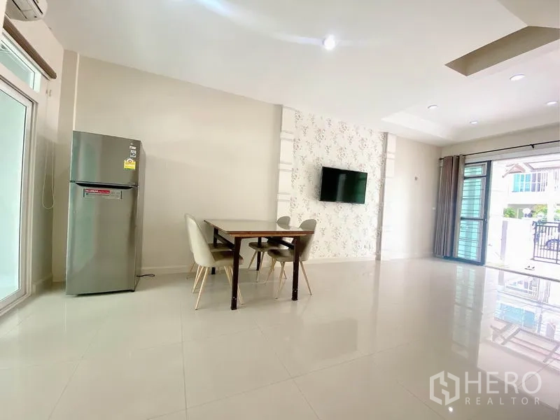 Townhouse for rent in Prawet, Bangkok - Bright open-plan living and dining area with glossy tile floors, dining set and wall-mounted TV.