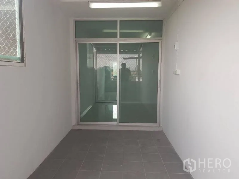 Shophouse for rent or sale in Lat Phrao, Bangkok - Small tiled area with frosted glass sliding door and ceiling light.