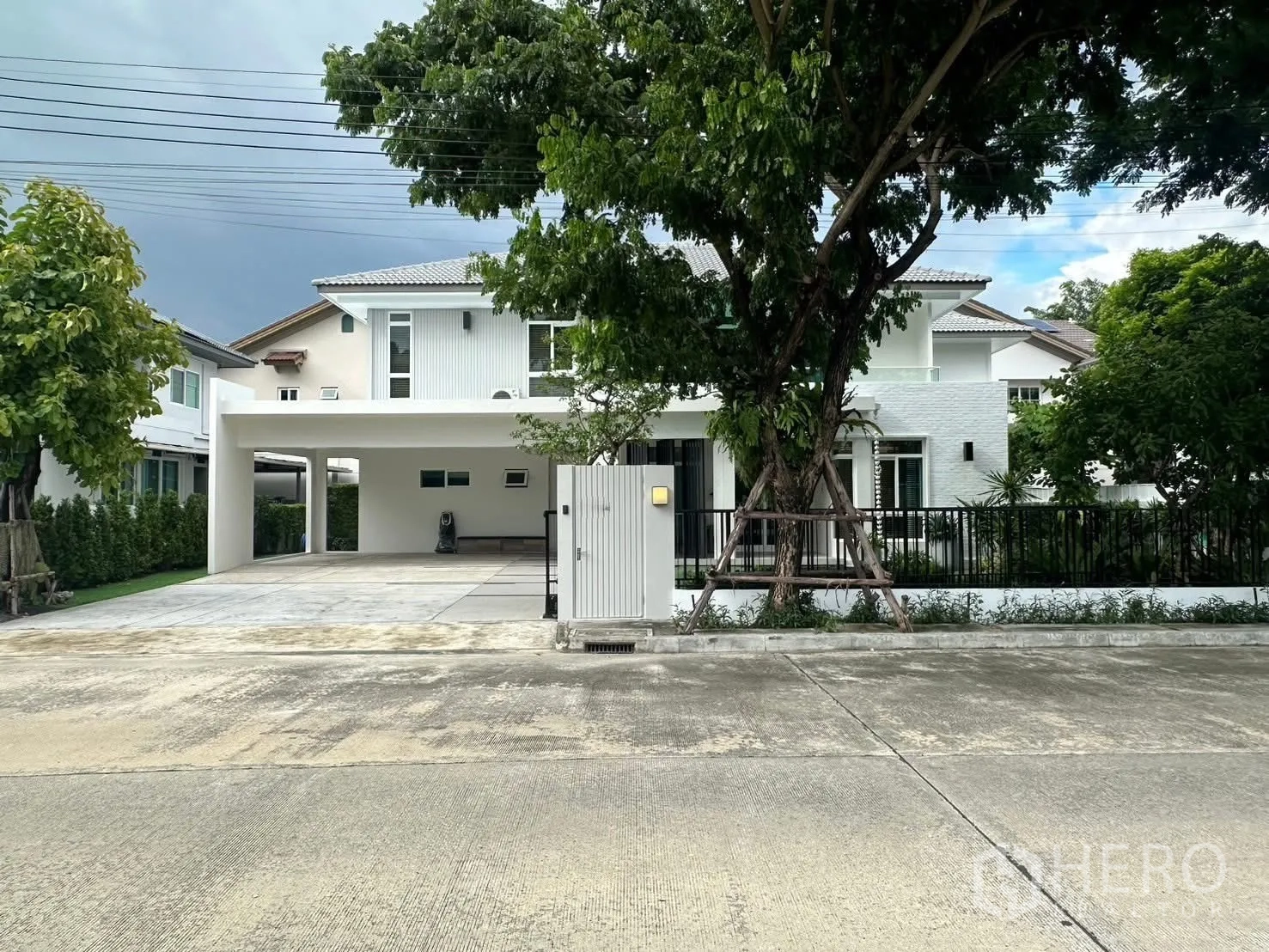 Detached House for rent in Bang Phli, Samut Prakan - Modern two-storey white detached house with gated entrance, wide driveway, and trees in front.