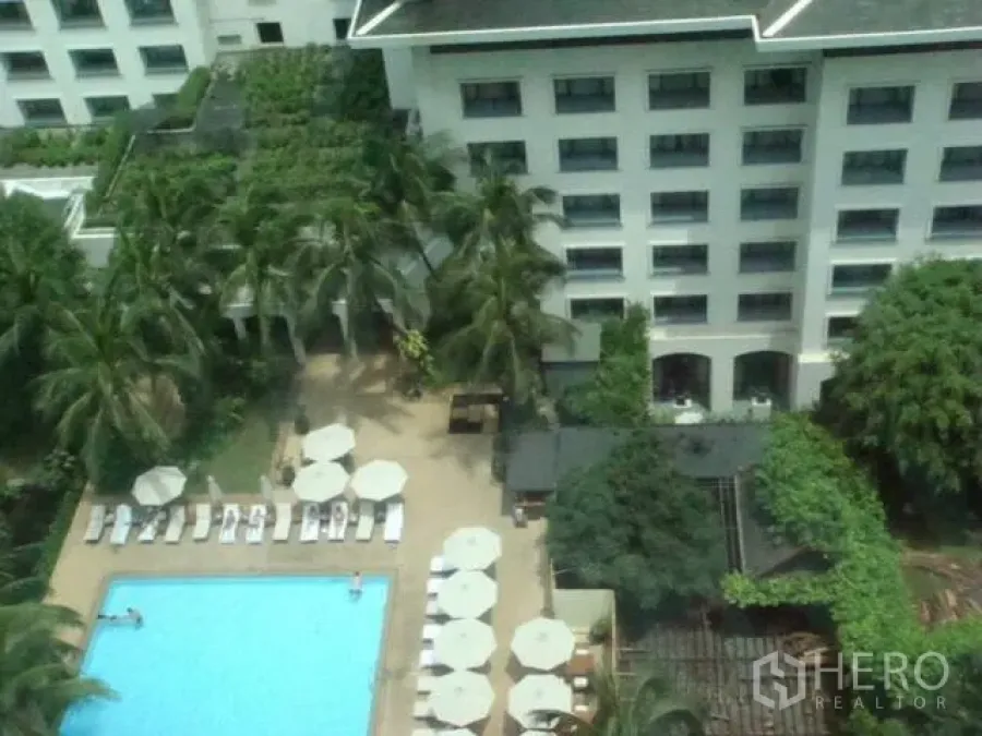 Condominium for rent in Pathum Wan, Bangkok - Aerial view of a condominium pool deck with sun loungers and palm trees in Pathum Wan.