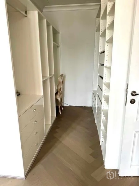Townhouse for rent in Watthana, Bangkok - Walk-in closet corridor fitted with white shelves and drawers.