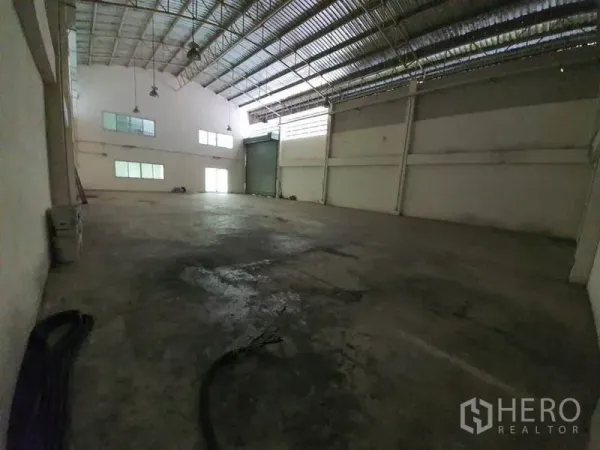 Factory for rent in Lam Luk Ka, Pathum Thani - Spacious warehouse interior featuring high steel roof, concrete floor, large roller door and office windows.