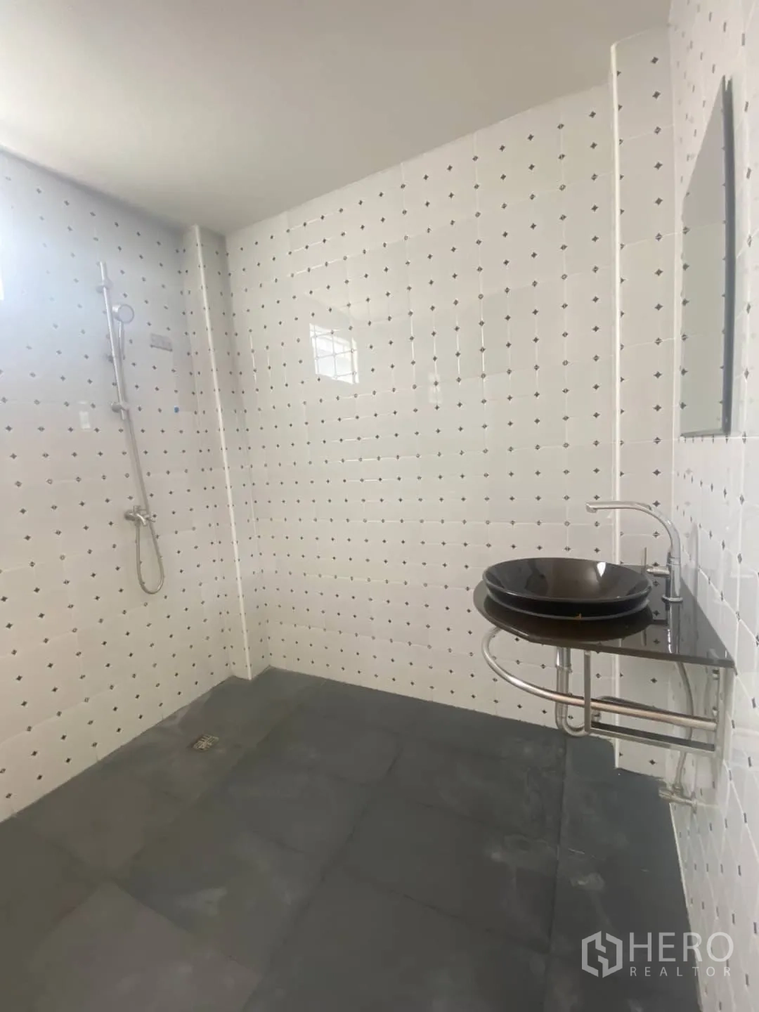 Home Office for sale - Bathroom with dotted white wall tiles and a round black vessel sink.