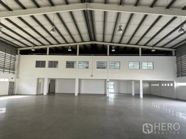 Factory for rent in Phra Nakhon Si Ayutthaya - Interior view toward mezzanine-style office block with multiple windows overlooking the factory floor.
