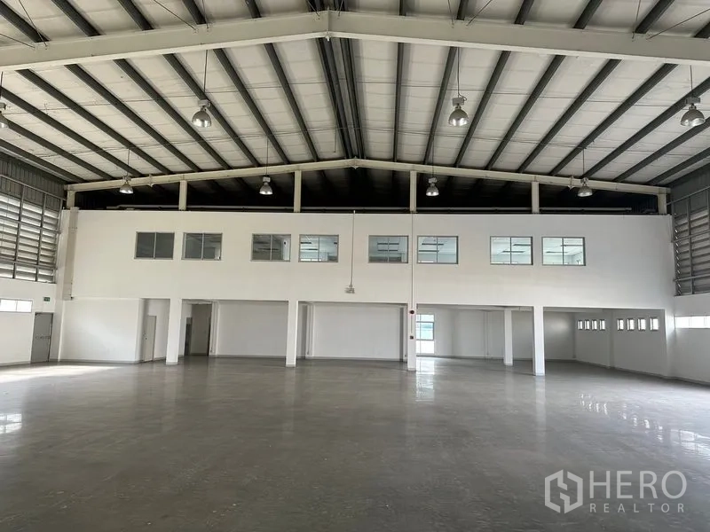 Factory for rent in Phra Nakhon Si Ayutthaya - Interior view toward mezzanine-style office block with multiple windows overlooking the factory floor.
