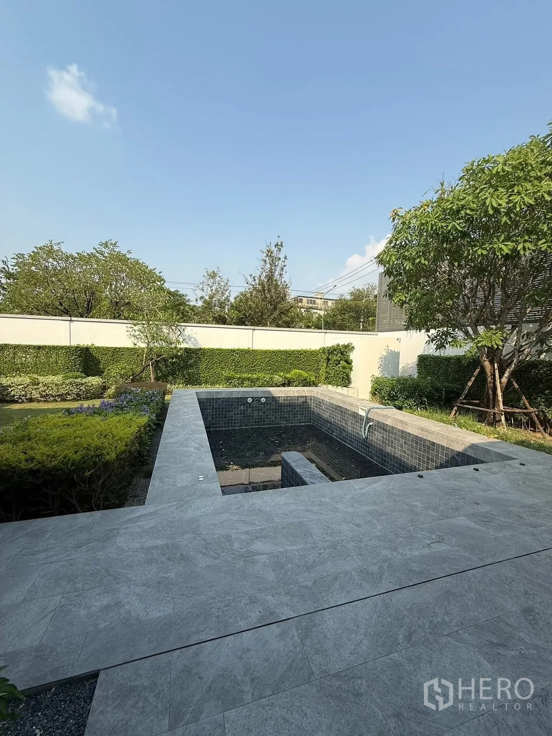 Detached House for rent in Bang Kapi, Bangkok - Garden view of the private pool surrounded by greenery and a boundary wall.