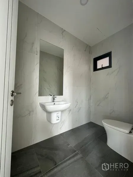 Warehouse for sale in Lam Luk Ka, Pathum Thani - Modern restroom with marble-look tiles, wall-mounted sink and toilet.