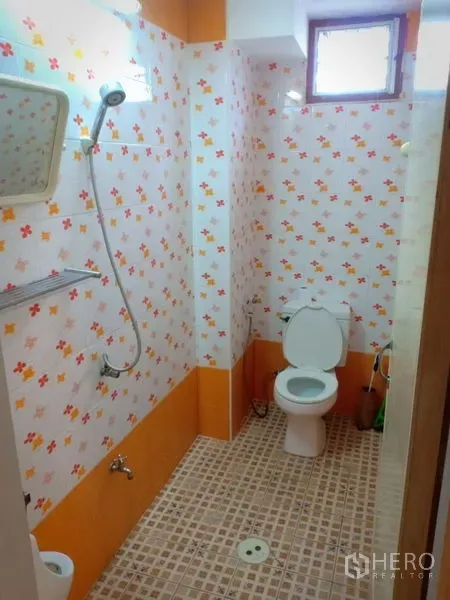 Townhouse for rent in Phra Khanong, Bangkok - Bathroom with shower, toilet and orange floral-patterned tiles.
