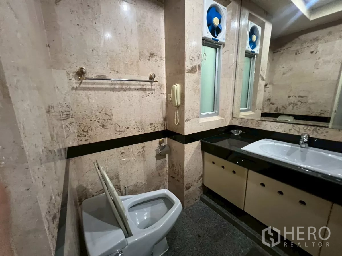 Shophouse for rent in Bang Rak, Bangkok - Marble-tiled restroom with dual-sink vanity and western toilet.