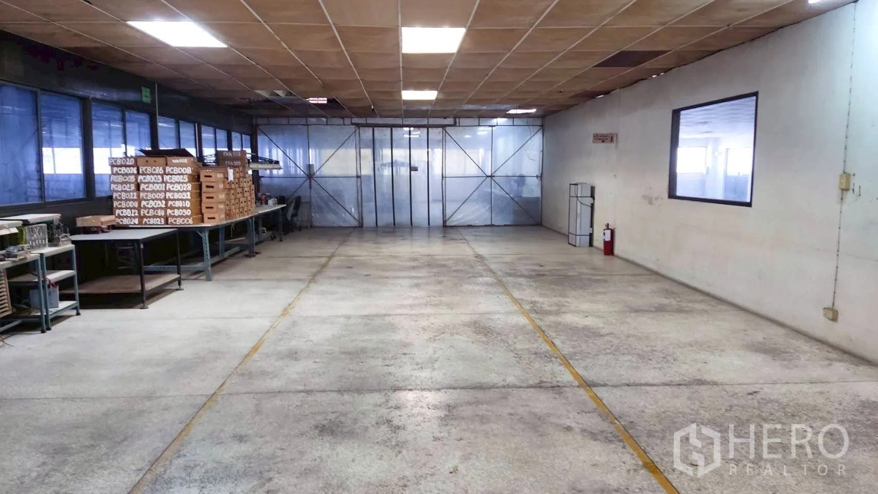 Factory for sale in Lat Krabang, Bangkok - Workshop area with worktables, storage racks, fluorescent lighting, and sliding metal doors.