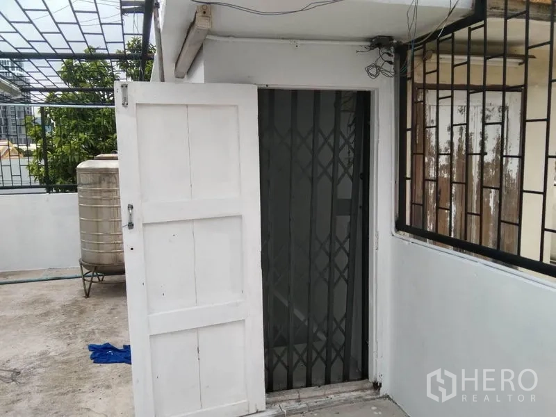 Shophouse for rent in Watthana, Bangkok - Rooftop entrance with white door and sliding security gate.