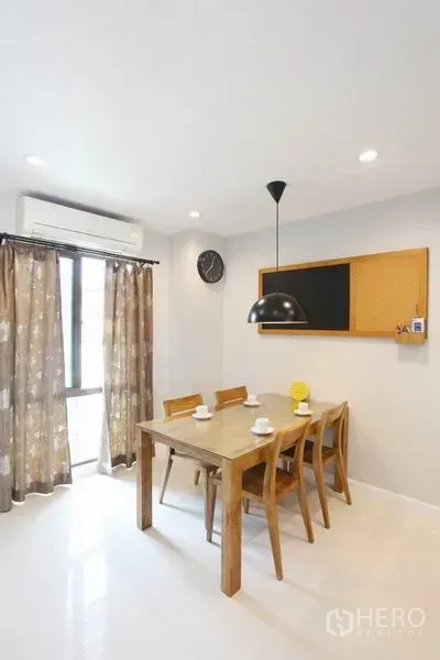 Townhouse for rent in Phra Khanong, Bangkok - Bright dining area with wooden table, pendant light and curtained window.