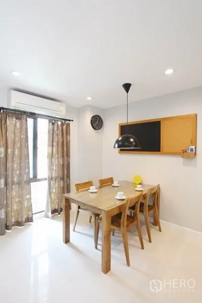 Townhouse for rent in Phra Khanong, Bangkok - Bright dining area with wooden table, pendant light and curtained window.