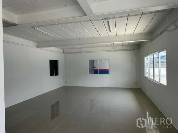 Warehouse for rent in Samut Prakan - Bright office room with tiled floor, white walls, windows and ceiling strip lights.