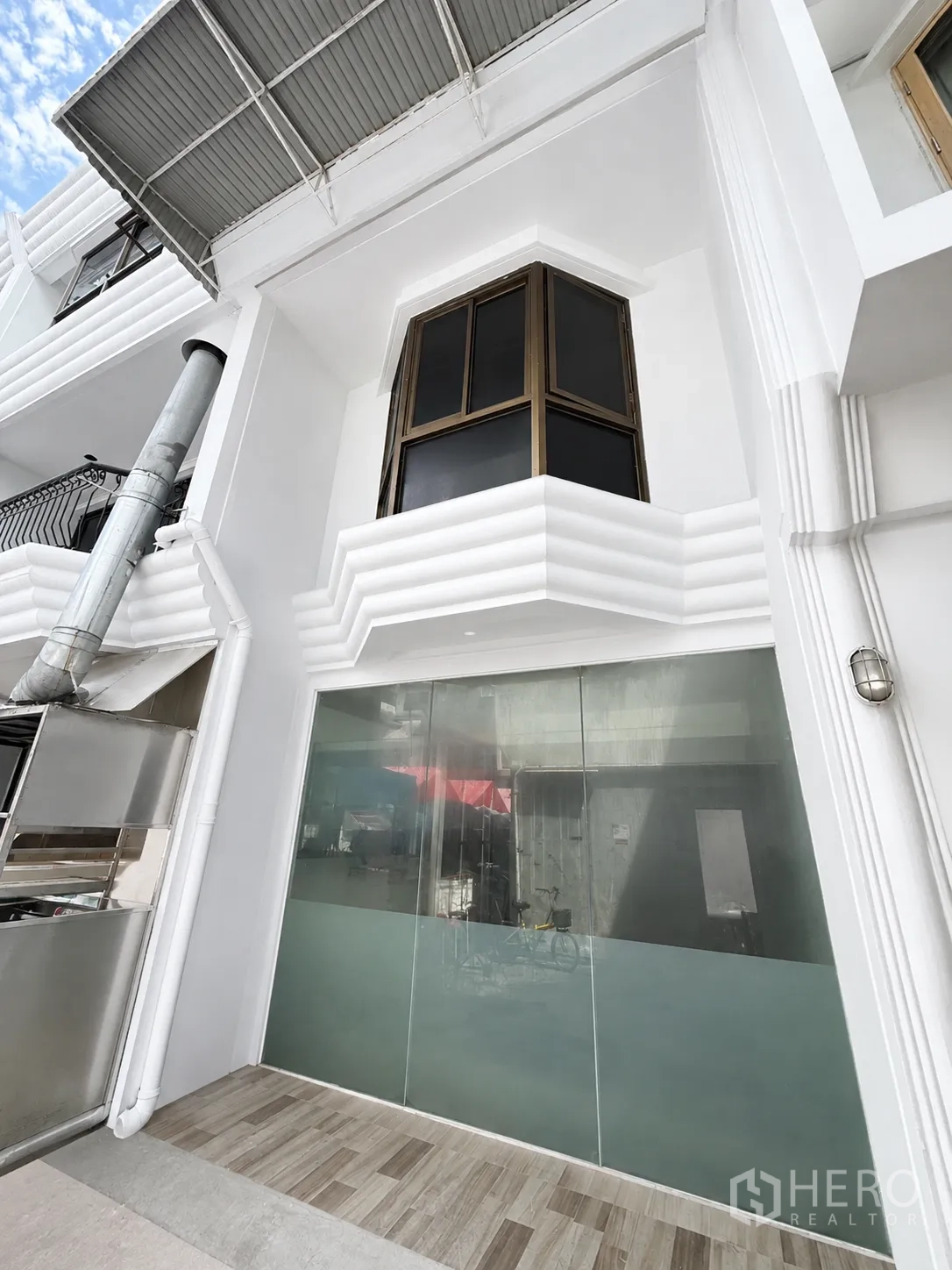 零售空间 for rent in Pathum Wan, Bangkok - 白色建筑立面，整面磨砂玻璃店面，带雨棚与二层凸窗。