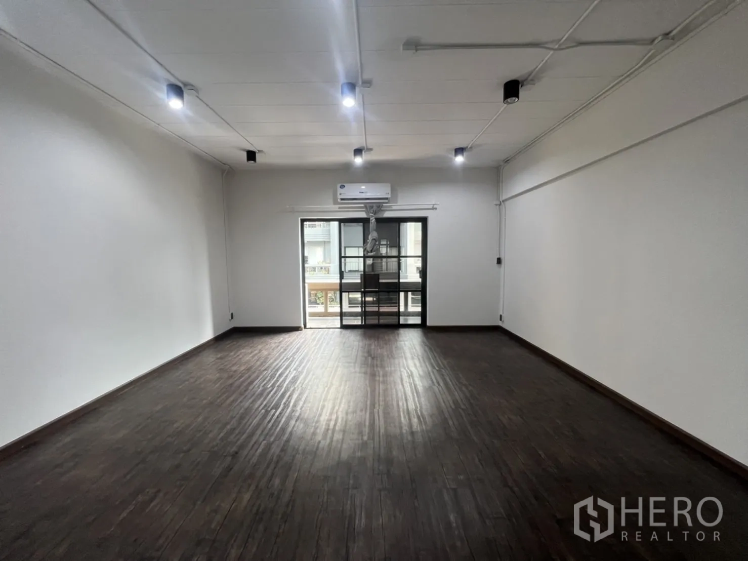 Retail Space for rent in Watthana, Bangkok - Large open-plan room with dark timber flooring, track lighting, air conditioning and balcony door.