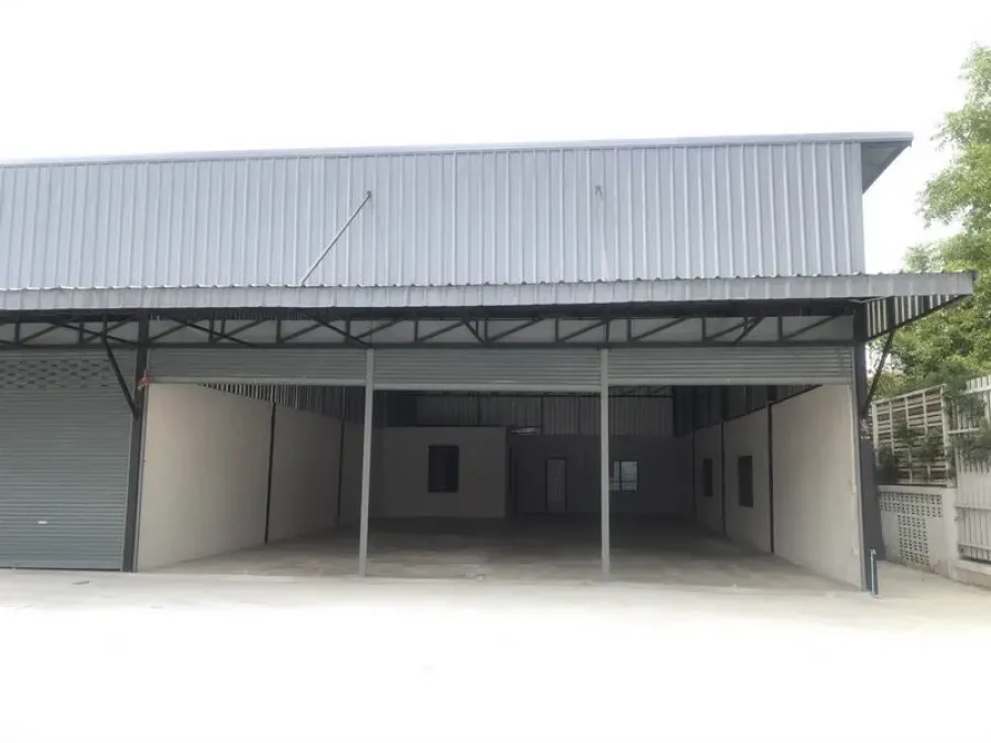 Warehouse for rent in Pathum Thani - Steel-clad warehouse exterior with wide covered loading bay and roller shutter in Khu Khot, Lam Luk Ka.