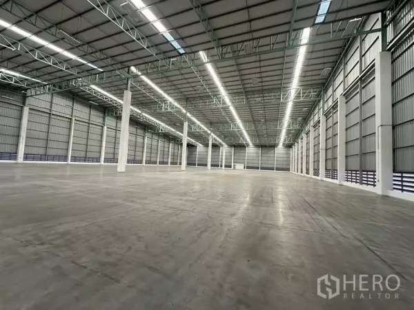 Factory for rent in Si Racha, Chon Buri - Clear-span factory hall with tall insulated walls, white columns and bright lighting.