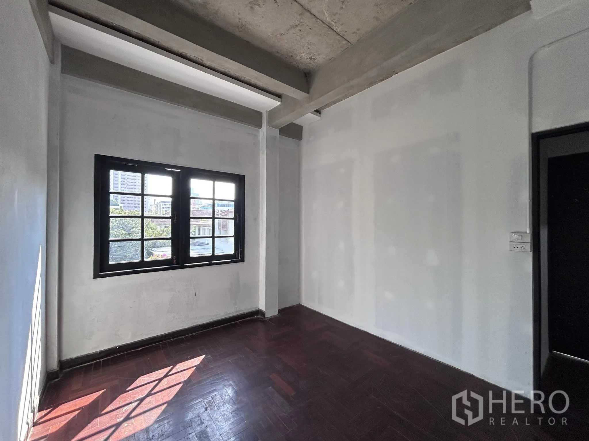 Home Office for rent or sale in Watthana, Bangkok - Room with exposed concrete ceiling beams, wood floor and a single window.