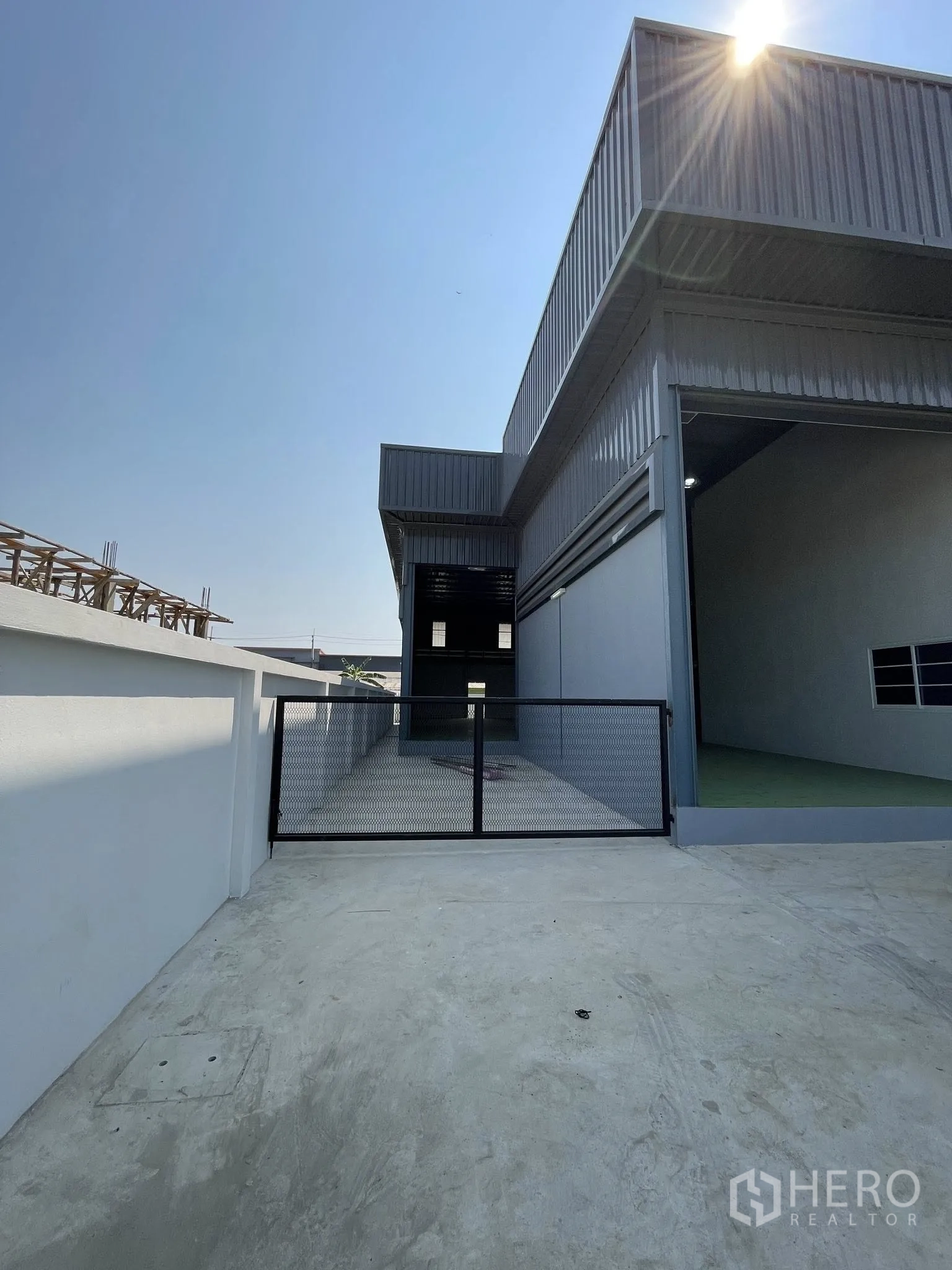 Factory for rent or sale in Bang Phli, Samut Prakan - Side entrance gate beside the factory with covered loading bay and wide paved access.