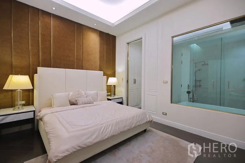 Detached House for rent or sale in Watthana, Bangkok - Master bedroom with warm accent wall and interior window to the ensuite bathroom.