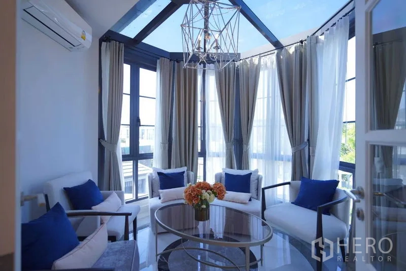 Detached House for sale in Bang Kapi, Bangkok - Sunroom lounge with glass ceiling, bay windows, and modern armchairs.