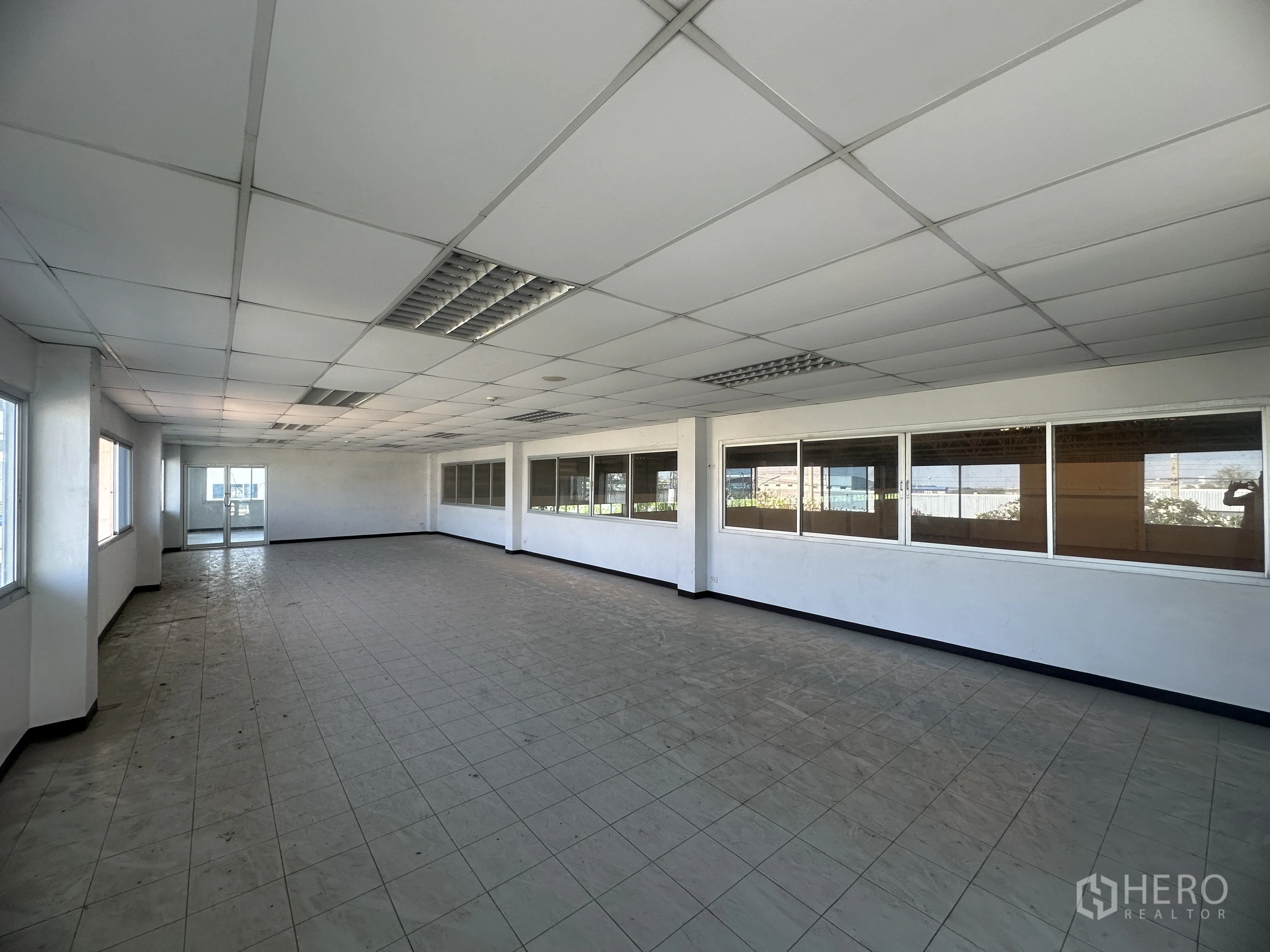 Factory for rent in Bang Pa-in, Phra Nakhon Si Ayutthaya - Upper‑floor open‑plan office with tiled flooring, long window line, and internal windows to the hall.