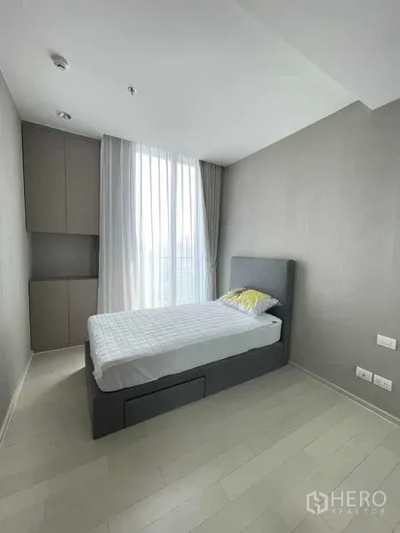 Condominium for rent in Pathum Wan, Bangkok - Bright bedroom with a single bed, floor-to-ceiling window and built-in wardrobe.