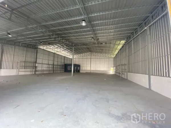 Warehouse for rent in Prawet, Bangkok - Clear-span warehouse interior with metal walls, roof lighting, and expansive concrete floor.