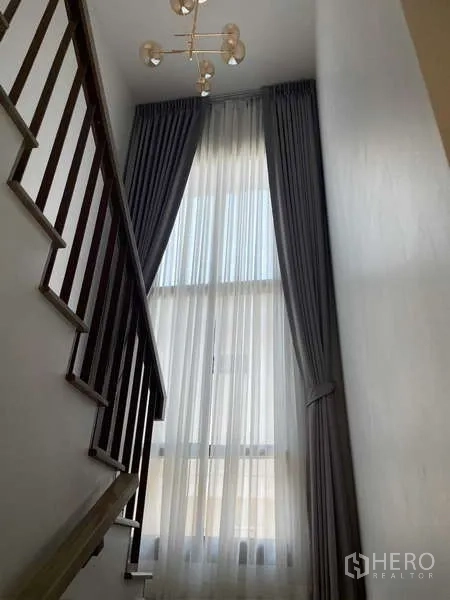 Detached House for rent in Bang Kapi, Bangkok - Staircase with tall window and layered curtains filling the space with natural light.