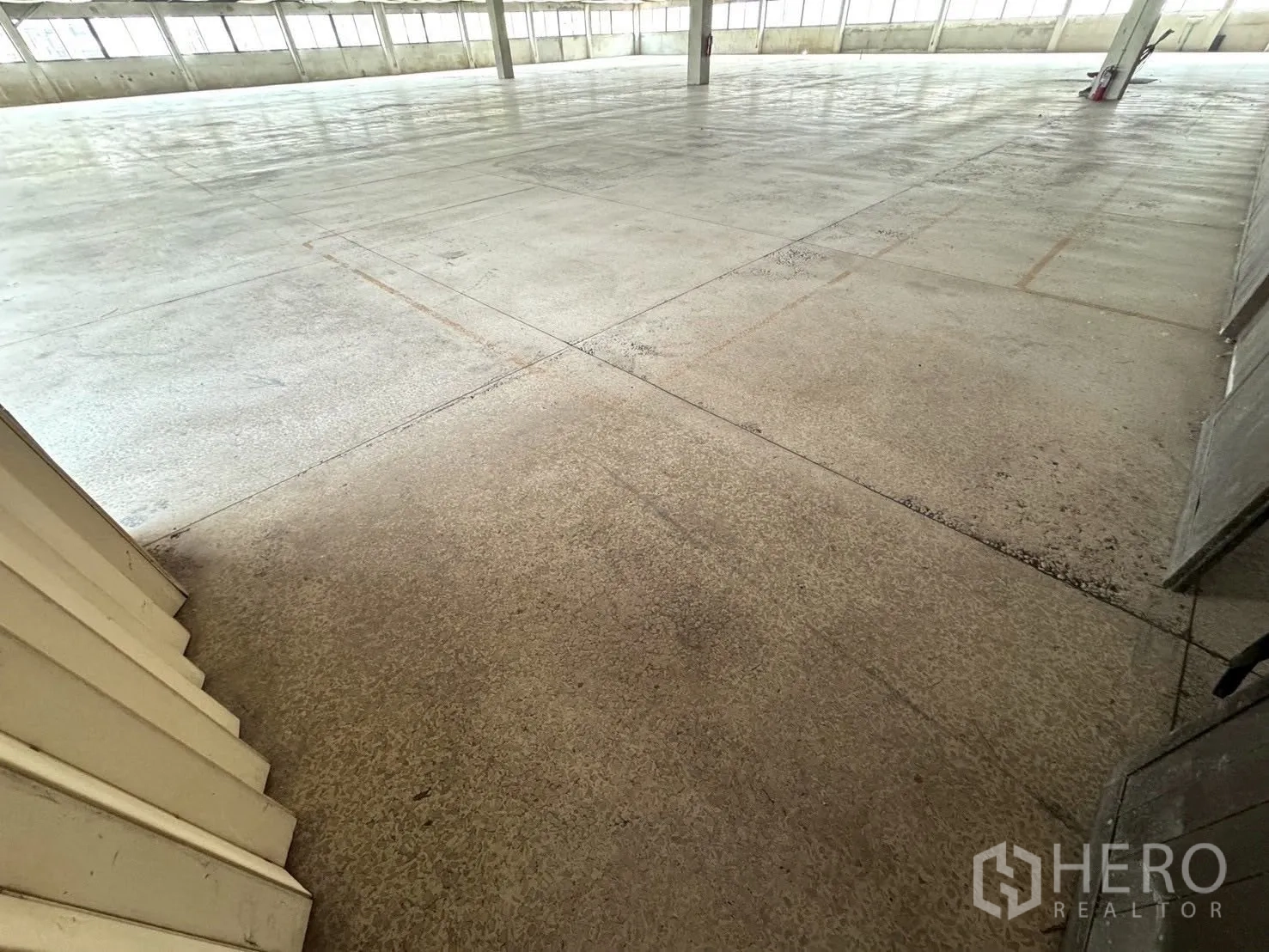 Factory for sale in Lat Krabang, Bangkok - Large interior floor with polished concrete, windows along the sides, and support columns.