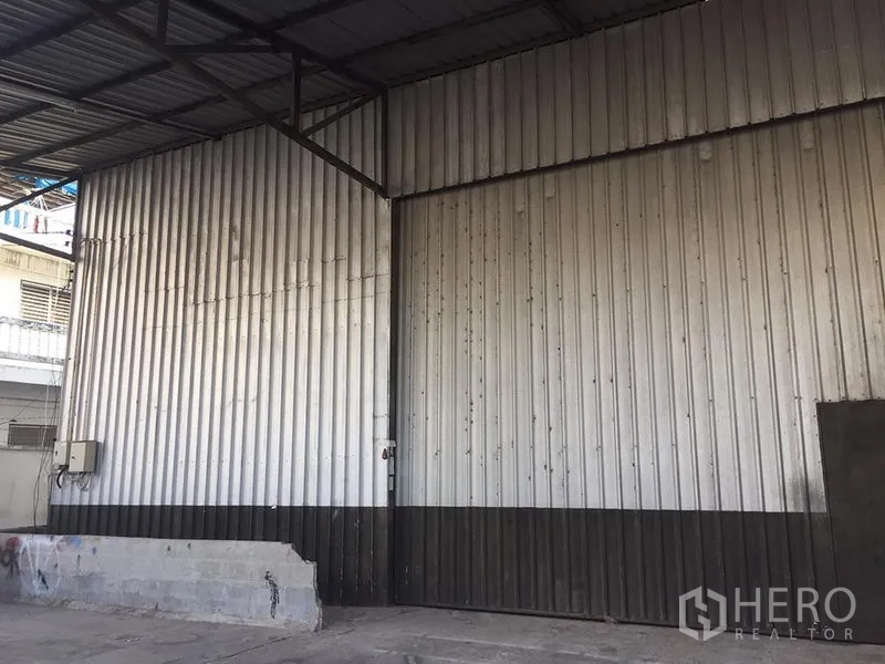 Warehouse for rent in Lat Krabang, Bangkok - Close-up of corrugated metal exterior wall and oversized sliding door of industrial warehouse.