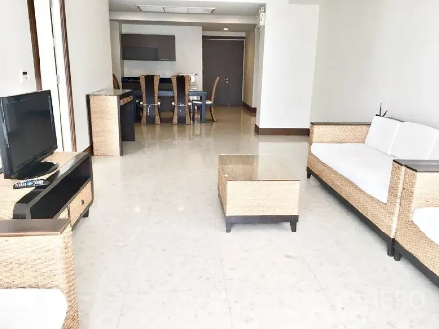 Condominium for rent in Khlong Toei, Bangkok - Spacious open living–dining area with rattan furniture and glossy tile floor.