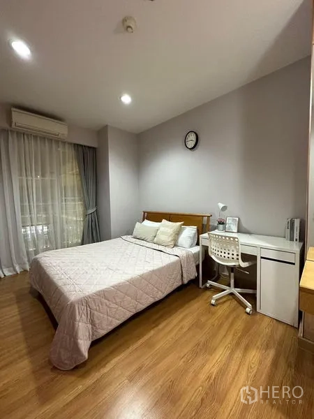 Condominium for rent in Khlong Toei, Bangkok - Bright bedroom with bed, study desk and chair, sliding balcony door with sheer curtains and wood floor.