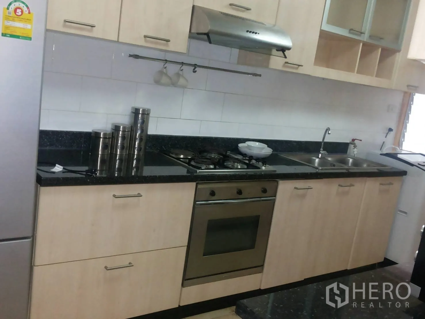 Apartment for rent in Khlong Toei, Bangkok - Fitted kitchen with gas hob, oven, range hood, double sink, and ample cabinetry.