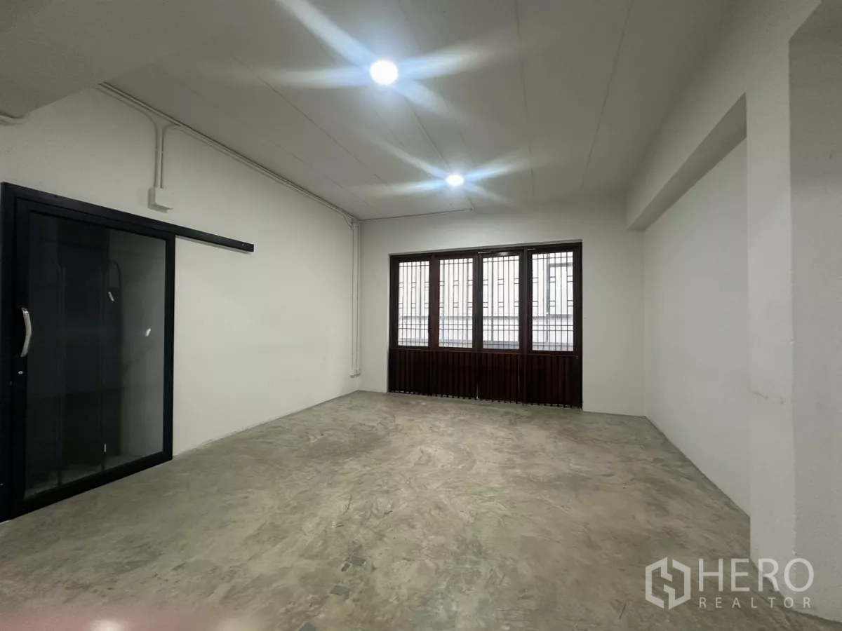 Home Office for rent in Pathum Wan, Bangkok - Spacious studio area with concrete flooring, barred windows and a black-framed sliding glass door.