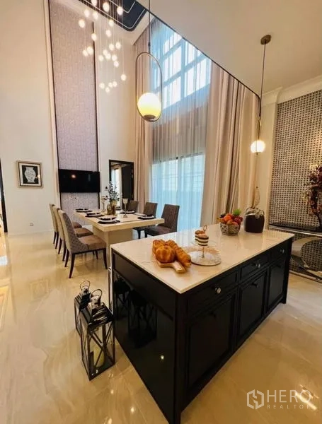 Detached House for rent or sale in Watthana, Bangkok - Contemporary kitchen with a large island, pendant lights and tall curtains.