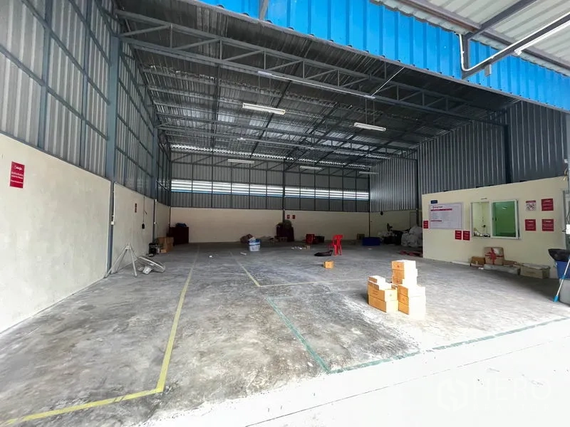 Warehouse for rent in Khlong Luang, Pathum Thani - Loading area and storage space with marked floor lines under blue canopy.