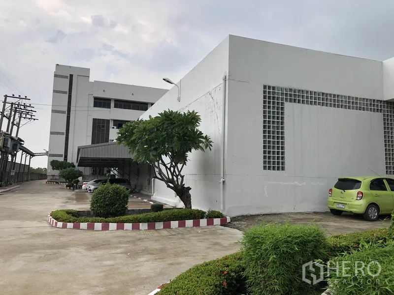 Factory for rent in Lat Krabang, Bangkok - Modern white factory exterior with wide driveway, landscaped shrubs and parking area in Lat Krabang.