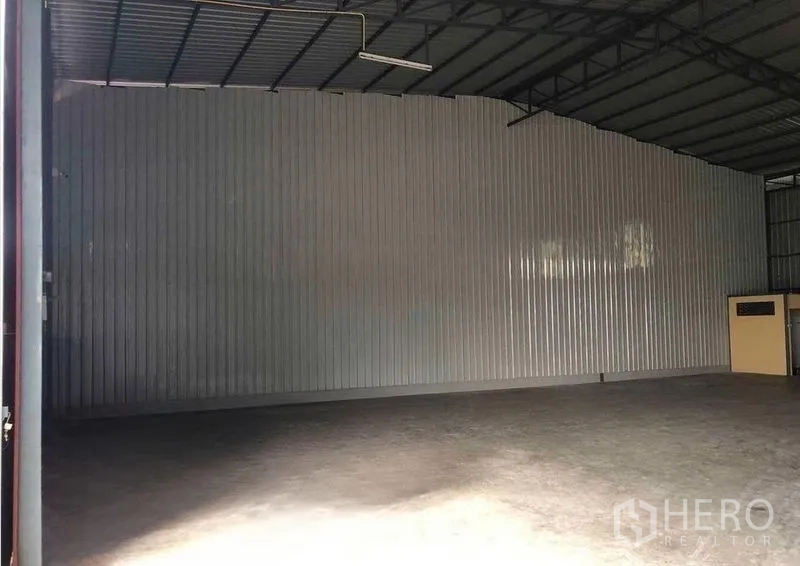 Warehouse for rent in Bang Kapi, Bangkok - Interior of the warehouse showing a high steel roof, corrugated walls, and smooth concrete floor.