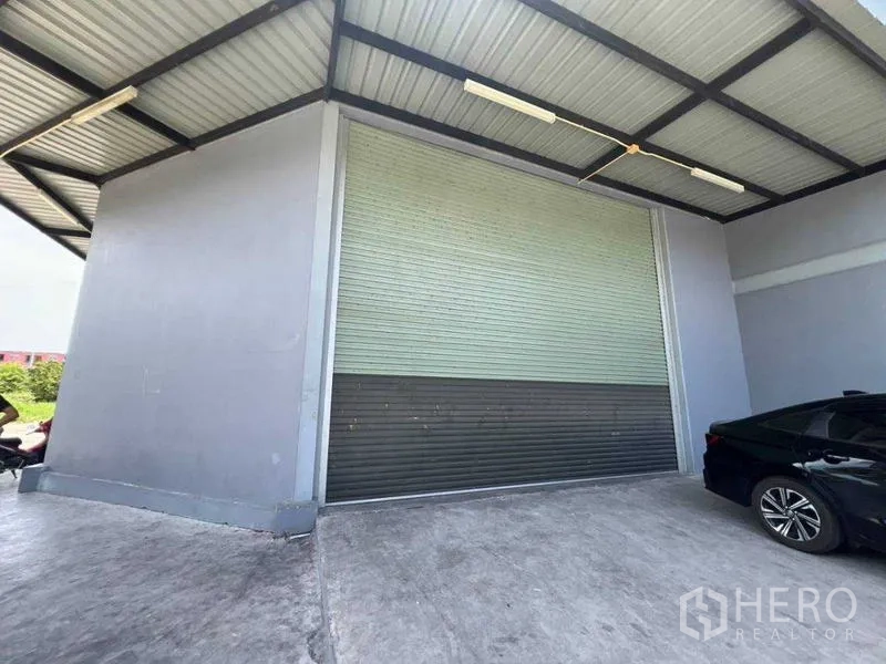 货栈 出租在Bang Khun Thian, Bangkok - 带顶棚的装卸区与大型卷帘门的仓库入口