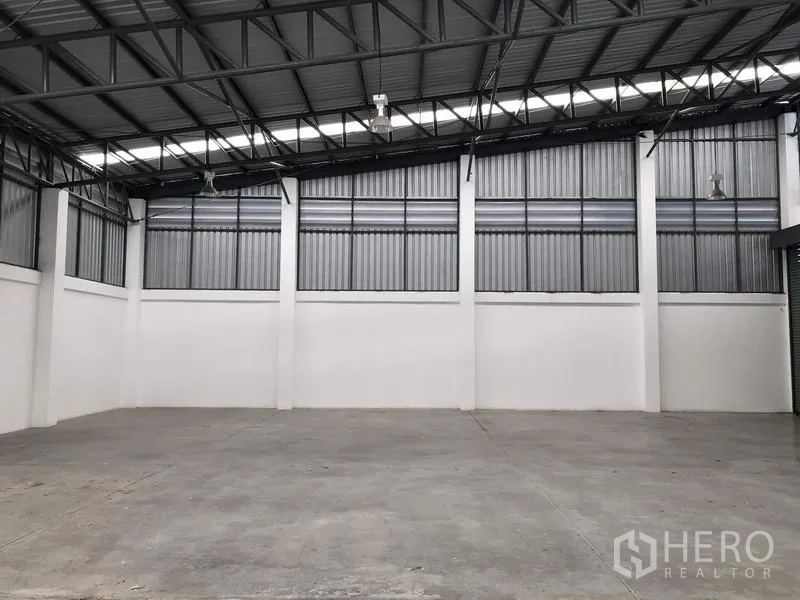 Warehouse for rent or sale in Lam Luk Ka, Pathum Thani - Empty warehouse space showing polished concrete floor, ventilated wall panels and skylight strips.