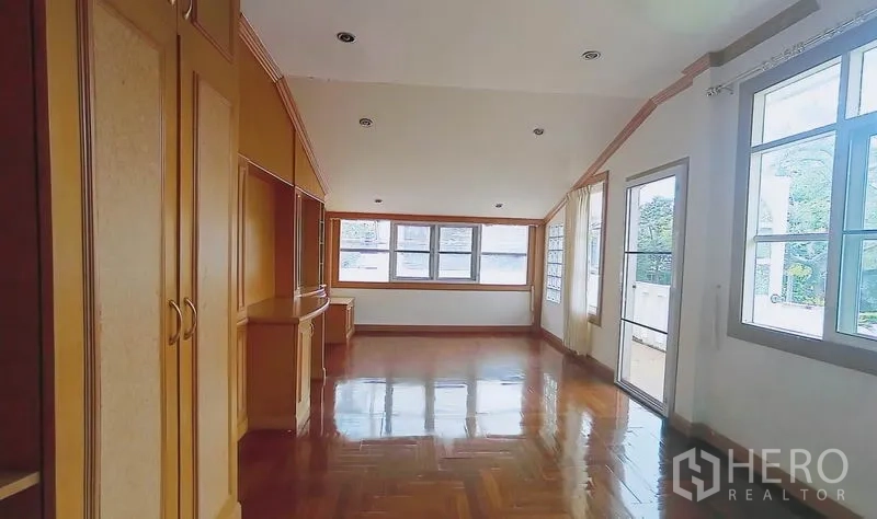 Detached House for sale in Bang Kapi, Bangkok - Spacious family room with wood floors, built-in shelves and a door to the balcony.