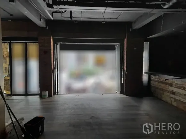 Shophouse for rent - Ground-floor retail space with wide street-facing entrance, brick columns, dark flooring and exposed ceiling.