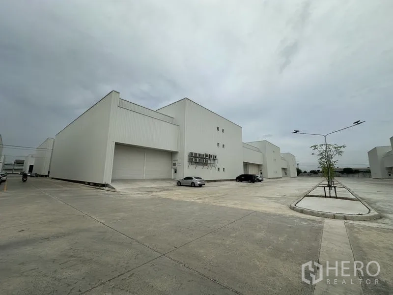Factory for rent in Pathum Thani - New white factory buildings with wide concrete yard and parking in a Khlong Luang industrial estate.