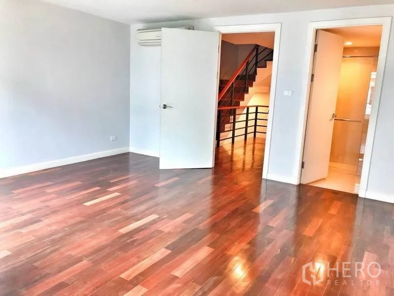 Townhouse for rent in Watthana, Bangkok - Spacious bedroom with polished wood floor and ensuite bathroom.